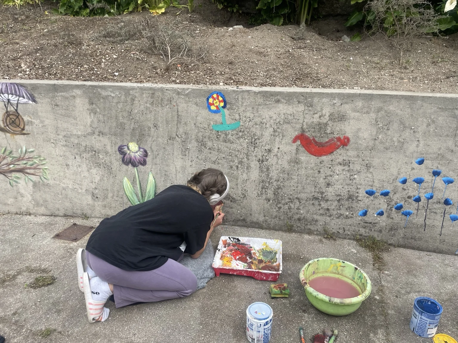 Voluntária a pintar um mural com elementos de natureza